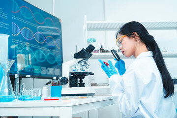 Female scientist in lab coat examining a petri dish with a magnifying glass in a modern laboratory....