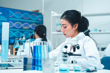 Asian female scientist in a white lab coat taking notes during a scientific experiment in a modern...