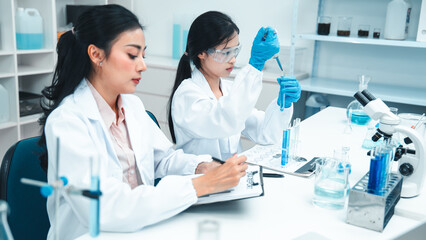 Female scientists working together in a laboratory. One is instructing while the other performs an...