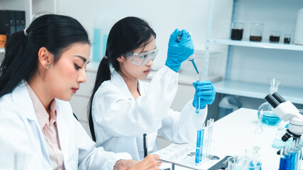 Female scientists working together in a laboratory. One is instructing while the other performs an...