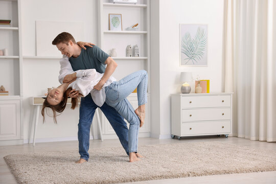 Happy young couple dancing together at home - Powered by Adobe