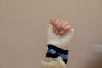Woman showing her pink nails with glitter manicure and warm winter sweater