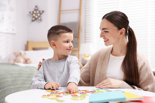 Dyslexia. Mother and her son learning letters at table indoors