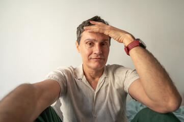 Mature man taking a selfie touching his forehead