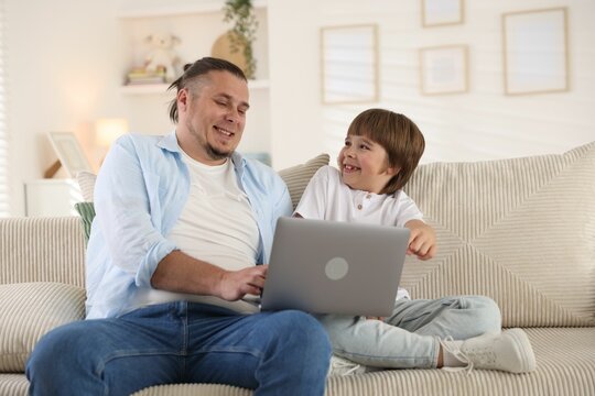 Father and his son watching something on laptop at home