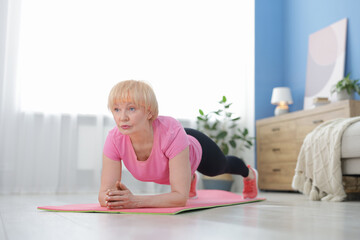 Senior woman in sportswear doing plank exercise at home