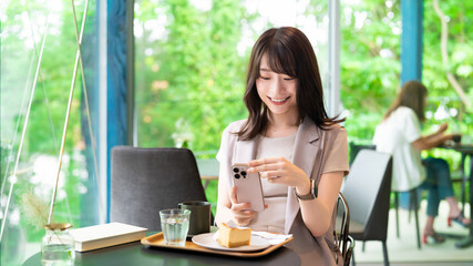 カフェでケーキの写真を撮影する女性