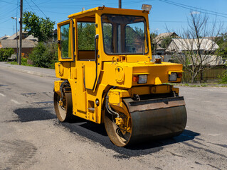 A large yellow road roller sitting on the side of a road