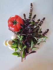 Juicy ripe red tomatoes, fresh basil and garlic cloves on a light background. Flatly. Fresh natural ingredients for cooking.