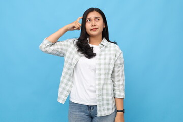 Young Asian woman looking confused or making mistake while scratching head, wearing casual clothes,...