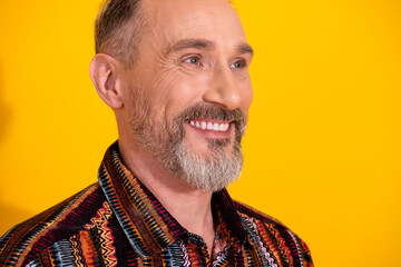 Cheerful mature man in colorful shirt smiling with vibrant yellow background exuding confidence and...