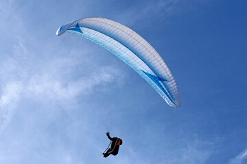 Paraglider flying in a blue sky	
