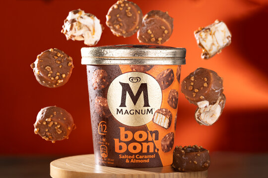 Studio shot of Magnum Bonbon Salted Caramel & Almond ice cream pack with floating pieces showcasing the product texture. Editorial illustrative image highlighting premium frozen dessert branding.