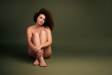 Natural beauty and self-acceptance showcased by a young woman with curly hair posing against a...