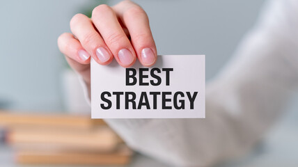 A person is holding a white card that says Best Strategy