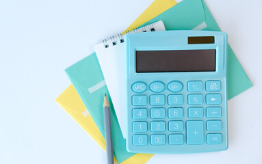 A blue calculator sits on top of a yellow envelope and a pencil