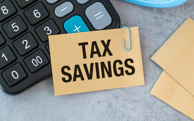 A calculator is on a table with a piece of paper that says Tax Savings