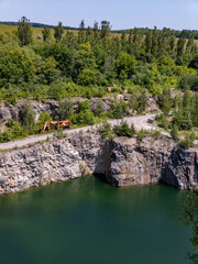 Flooded granite quarry surrounded by trees and stones