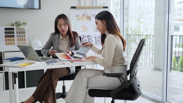 Asian Women Discussing Interior Design Color Palette Choice for Home Renovation Project in Modern Office Interior Color Matching and Selection for House Decoration Ideas