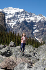 Naklejka premium Girl in pink shirt standing on boulders in mountains, Banff