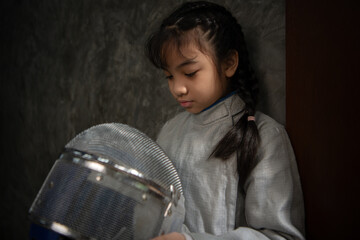 Before the tournament day, a girl dressed in fencing gear are rehearsing in gym