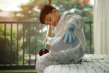A girl in fencing gear is sitting and rest on the bed, exhausted from the training that just ended