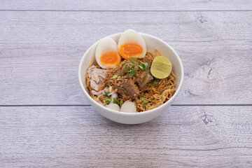 bowl of noodles with vegetables on wooden table.