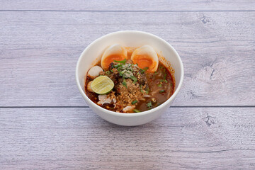 bowl of noodles with vegetables on wooden table.