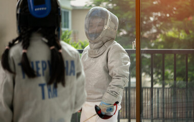 Before the tournament day, a boy and girl dressed in fencing gear are rehearsing in gym