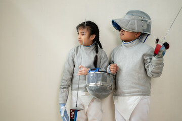 Before the tournament day, a boy and girl dressed in fencing gear are rehearsing in gym