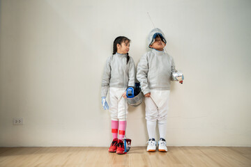 Before the tournament day, a boy and girl dressed in fencing gear are rehearsing in gym