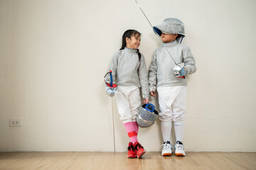 Before the tournament day, a boy and girl dressed in fencing gear are rehearsing in gym