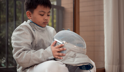 Before the tournament day, a boy dressed in fencing gear are rehearsing in gym