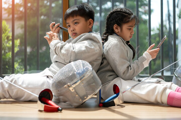 A girl and boy in fencing gear resting before practicing fencing in preparation