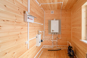 Wooden room with electrical panel, boiler, and pipes. Clean and functional, showcasing utilities