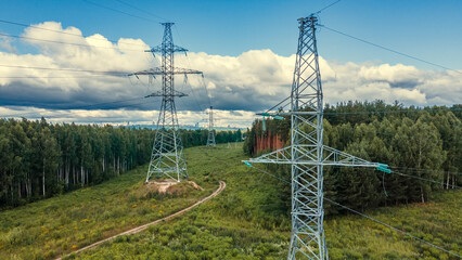 Power lines in a green field in the sunny summer day. Electrical substation. Drone view.