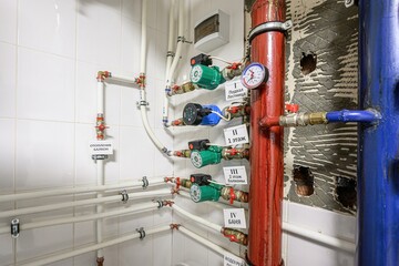 network of pipes and pumps is shown on a tiled wall with labeled connections, indicating a complex...