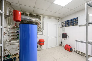 utility room features a blue water heater, pipes, electrical panel, white door, and a red generator...