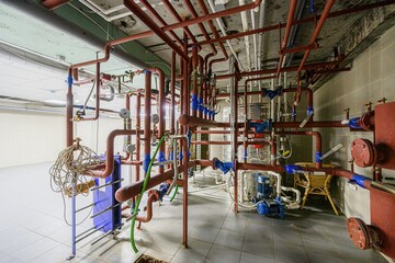 complex network of pipes, valves, and gauges in a utility room. Industrial, messy, and functional