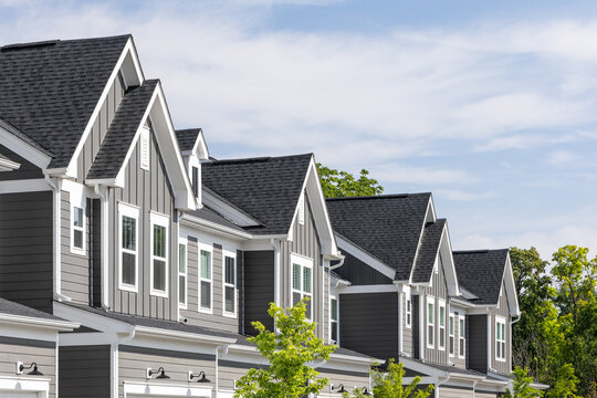 Detail of a row of grey and white modern farmhouse townhomes with board and batten and horiztonal siding. 