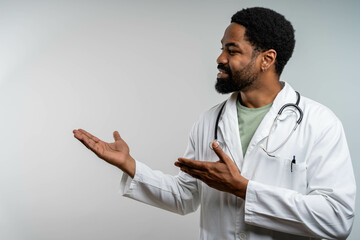 smiling african american doctor pointing at copy space on isolated background, confident and...