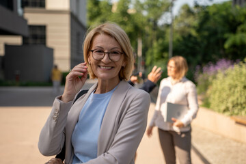 beautiful mature businesswoman outdoors in modern business district, smiling with confidence and...