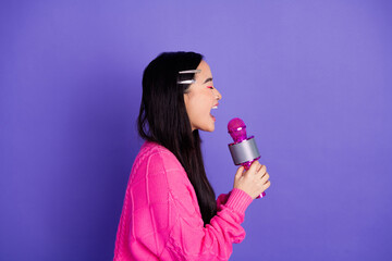 Young woman singing passionately with a vibrant microphone against a cheerful purple backdrop,...