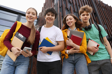 Group of happy teenagers near building outdoors, low angle view