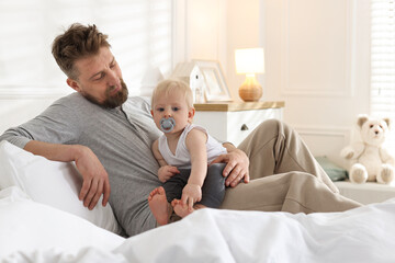 Bedtime. Happy father with his cute little baby on bed at home