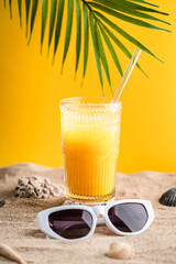 Colourful orange cocktail in a tall glass on a sand of a golden beach at a tropical holiday resort background an enjoyable summer vacation. High quality photo
