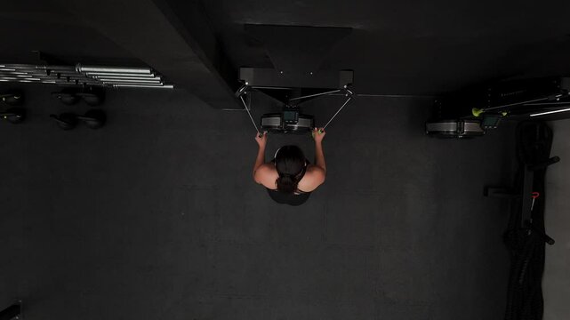 Mexican woman doing pull-ups on a ski machine in a gym