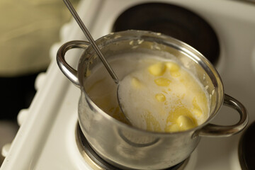 stirring sweet cream ghee with a metal spoon with holes