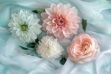 Obraz premium Delicate pastel flowers arranged on a light blue sheer fabric.