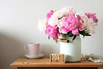 Pink and white peonies in a can and a wooden calendar showing july 5th